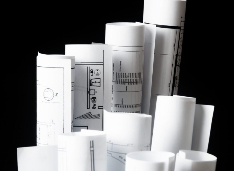 rolls of architecture blueprints and house plans on the black background